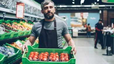 A retail worker handling fresh produce in a supermarket; illustrative image for a MyColes employee portal guide.