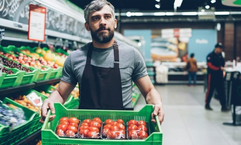 A retail worker handling fresh produce in a supermarket; illustrative image for a MyColes employee portal guide.