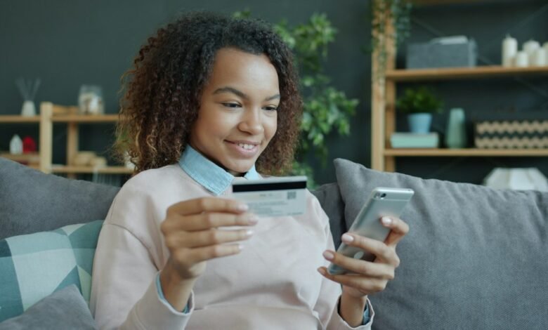 Person using a smartphone and payment card at home; illustrative image for an online banking guide, not a St.George Bank app screenshot