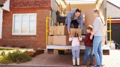 Family unloading moving boxes from a removal truck outside their house