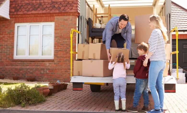Family unloading moving boxes from a removal truck outside their house
