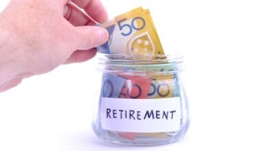 Hand placing Australian notes into a retirement savings jar