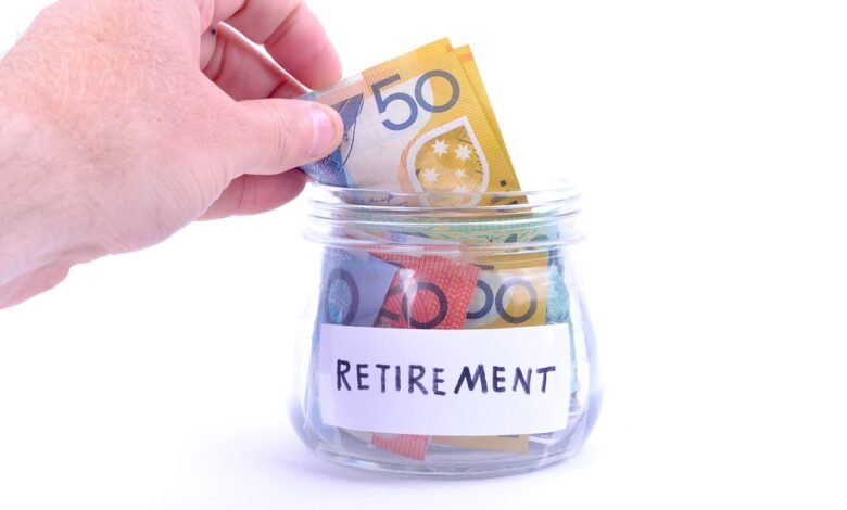 Hand placing Australian notes into a retirement savings jar