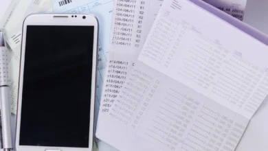 Smartphone next to bank account transaction records