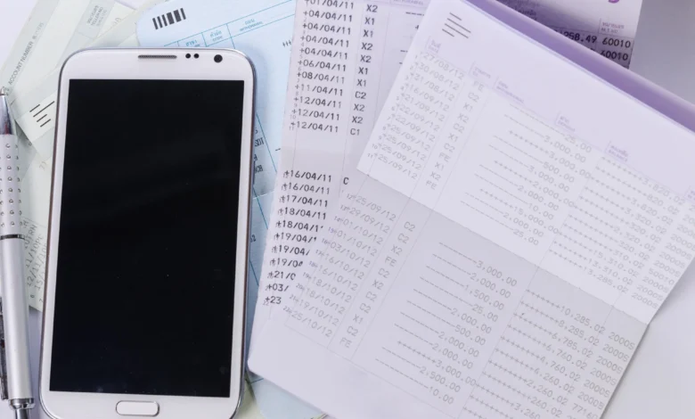 Smartphone next to bank account transaction records